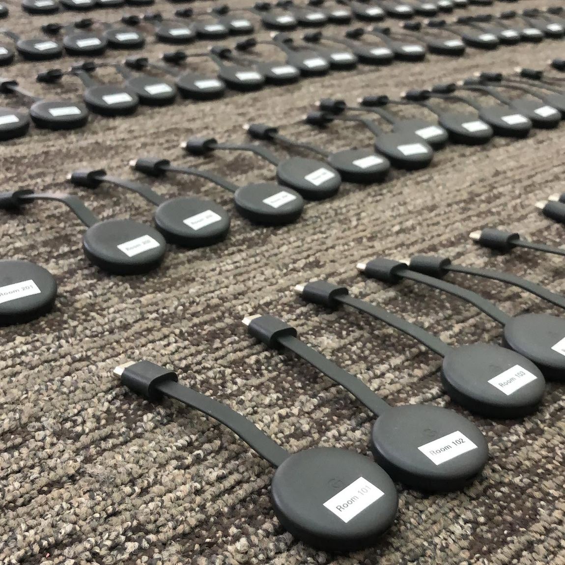Rows of hotel room streaming devices labelled by room number, ready for bulk installation